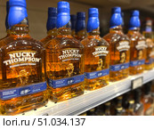 A row of bottles of Nucky Thompson whiskey on a shelf. Russia. Moscow. 08.08.25. Редакционное фото, фотограф Ярославский Максим / Фотобанк Лори