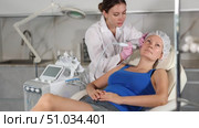 Adult woman cosmetologist doing cleansing procedure to young woman. Стоковое видео, видеограф Яков Филимонов / Фотобанк Лори