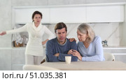 Three people are in bright kitchen, woman expresses her displeasure to man and old woman calms him down. Стоковое видео, видеограф Яков Филимонов / Фотобанк Лори