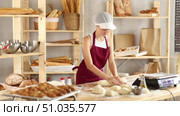 Confident teenage female learner shaping dough into rolls on the countertop in bakery. Стоковое видео, видеограф Яков Филимонов / Фотобанк Лори