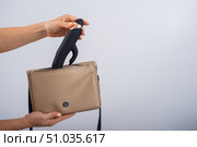 A woman puts a dildo in a handbag on a white background. Close-up of female hands with a black vibrator. Стоковое фото, фотограф Михаил Решетников / Фотобанк Лори