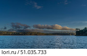 Beautiful calm lake. Ripples on the blue water. Green vegetation on the shores. The clouds in the sky are illuminated by the golden evening light. Madagascar. Lake Mantasoa. Стоковое фото, фотограф Вера Ивановна Кубарева / Фотобанк Лори