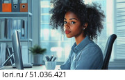 A young woman with curly hair concentrates on her work at a computer in a stylish office filled with books and greenery, creating a productive atmosphere. Стоковое AI-видео, аниматор Данила Большаков / Фотобанк Лори