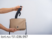 A woman puts a dildo in a handbag on a white background. Close-up of female hands with a black vibrator. Стоковое фото, фотограф Михаил Решетников / Фотобанк Лори