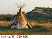Teepee standing in a field at sunset in the american prairie. Стоковое AI-изображение, AI-художник Иван Рябоконь / Фотобанк Лори