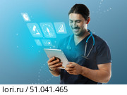 Healthcare professional using tablet for patient data management in modern clinic setting, focused on improving medical outcomes. Стоковое фото, фотограф Сергей Толмачёв / Фотобанк Лори