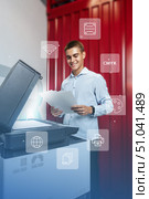 Young man smiling while using a multifunction printer for printing documents in a modern workspace. Стоковое фото, фотограф Сергей Толмачёв / Фотобанк Лори