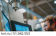 Young technician operates advanced machinery in modern manufacturing facility during daytime. Стоковое AI-видео, аниматор Сергей Толмачёв / Фотобанк Лори