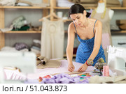 Young female seamstress attaching template to fabric. Стоковое фото, фотограф Яков Филимонов / Фотобанк Лори