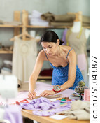 Young female seamstress attaching template to fabric. Стоковое фото, фотограф Яков Филимонов / Фотобанк Лори
