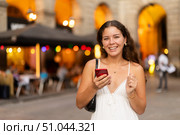 In evening, smiling girl with smartphone walks along city street Placa Real. Стоковое фото, фотограф Яков Филимонов / Фотобанк Лори