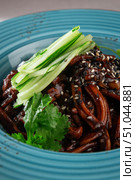 Traditional Korean jajangmyeon noodles with rich black bean sauce, fresh cucumber, sesame seeds and herbs served in a rustic blue ceramic bowl. Стоковое фото, фотограф Aleksandr Gavrilychev / Фотобанк Лори