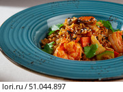Spicy Korean style kimchi fried rice with shrimp, bell pepper, sesame seeds and fresh cilantro served in a rustic blue ceramic bowl on white background. Стоковое фото, фотограф Aleksandr Gavrilychev / Фотобанк Лори