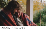 Couple enjoying cozy moments together under a blanket on a swing during autumn. Стоковое AI-видео, аниматор Сергей Толмачёв / Фотобанк Лори
