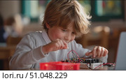 Young boy engaged in electronics project at school during afternoon class. Стоковое AI-видео, аниматор Сергей Толмачёв / Фотобанк Лори