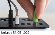 Modern convenient multi-port usb charger for devices. Close-up of a female hand plugging multi-colored cables into a power outlet. Macro. Стоковое фото, фотограф Михаил Решетников / Фотобанк Лори