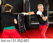 Elderly man practices kicking and punching with a trainer in gym. Стоковое фото, фотограф Яков Филимонов / Фотобанк Лори