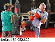 Mature man practicing foot strikes on kick shield with trainer. Стоковое фото, фотограф Яков Филимонов / Фотобанк Лори