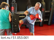 Mature man practicing foot strikes on kick shield with trainer. Стоковое фото, фотограф Яков Филимонов / Фотобанк Лори