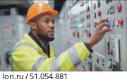 Electricity technician operates control panel in modern facility during day shift at industrial site. Стоковое AI-видео, аниматор Сергей Толмачёв / Фотобанк Лори
