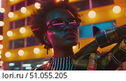 African American woman wearing sunglasses stands confidently in front of modern building, sunlight casting shadows across scene. Стоковое AI-видео, аниматор Данила Большаков / Фотобанк Лори