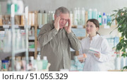 Mature man pharmacy client suffers from headache. Girl pharmacist offer help. Стоковое видео, видеограф Яков Филимонов / Фотобанк Лори