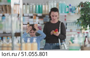 Woman stands in a pharmacy and checks her daughter's hair for lice. Child stands in the pharmacy with mother in search of remedies and shampoos for lice. Стоковое видео, видеограф Яков Филимонов / Фотобанк Лори