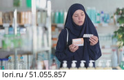 Uncertain young Muslim female client trying to choose medical preparation in chemist's shop. Стоковое видео, видеограф Яков Филимонов / Фотобанк Лори