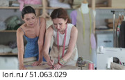 Women tailor draw dress pattern with curve ruler on paper and participate in creating pattern. Craftsman perform paper prototype of product parts, drawing paper pattern for dressmaking. Стоковое видео, видеограф Яков Филимонов / Фотобанк Лори