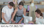 Two focused students are making dress detail and others using stitching machine during sewing class. Стоковое видео, видеограф Яков Филимонов / Фотобанк Лори