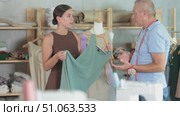Dissatisfied young woman client with sewn dress quarreling with elderly man tailor in sewing workshop. Стоковое видео, видеограф Яков Филимонов / Фотобанк Лори