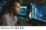 Coder engages in programming at a tech hub with multiple computer screens displaying code and digital graphics. Стоковое AI-видео, аниматор Сергей Толмачёв / Фотобанк Лори