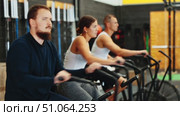 Concentrated sporty young bearded man intensely working out on stationary air bicycle in fitness gym. Healthy active lifestyle concept Focused motivated bearded guy leading healthy active lifestyle doing cardio workout on air resistance bike in gym. Стоковое видео, видеограф Яков Филимонов / Фотобанк Лори