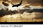 Passenger airplane landing at sunset over airport fence. Стоковое видео, видеограф Mikhail Davidovich / Фотобанк Лори