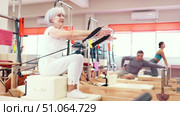 Elderly woman in sportswear training with straps in pilates studio. Стоковое видео, видеограф Яков Филимонов / Фотобанк Лори