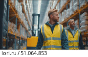 Men in safety vests check inventory in large warehouse during daytime. Стоковое AI-видео, аниматор Сергей Толмачёв / Фотобанк Лори