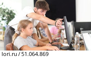 Concerned preteen girl sitting at computer while trainer explaining him something during IT courses. Стоковое видео, видеограф Яков Филимонов / Фотобанк Лори