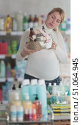 Smiling expecting mother holding elegantly wrapped wicker basket filled with bath and body care products in store, considering purchasing for self-care during pregnancy. Стоковое видео, видеограф Яков Филимонов / Фотобанк Лори