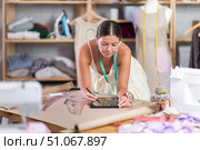 Young female dressmaker drawing on tablet in sewing workshop. Стоковое фото, фотограф Яков Филимонов / Фотобанк Лори