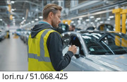 Factory worker conducts quality check on vehicles in automotive assembly line. Стоковое AI-видео, аниматор Сергей Толмачёв / Фотобанк Лори