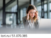 Красивая молодая бизнесвумен с головной болью сидит в современном офисе за письменным столом с ноутбуком. Стоковое AI-изображение, AI-художник Максим Коломыченко / Фотобанк Лори