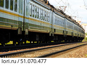 A train is traveling down the tracks with a green and yellow stripe. Russia. Moscow oblast. 14.08.25. Редакционное фото, фотограф Ярославский Максим / Фотобанк Лори