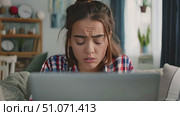 Woman looks surprised while sitting on a couch in her living room. She is using a laptop computer. Стоковое AI-видео, аниматор Данила Большаков / Фотобанк Лори