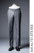 Mannequin wearing gray dress pants and black shoes on gray background. Стоковое AI-изображение, AI-художник Юрий Поздников / Фотобанк Лори