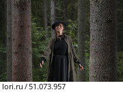 A woman in a long coat and hat enjoys a peaceful moment in the forest.ы. Стоковое фото, фотограф Happyphotons / Фотобанк Лори