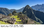 Panoramic view of the famous Machu Picchu. Ruins of a lost Inca city in the highlands. Dilapidated stone buildings, terraces, green grass. The high mountain of Wayna Pikchu against the blue sky. Peru. Стоковое фото, фотограф Вера Ивановна Кубарева / Фотобанк Лори