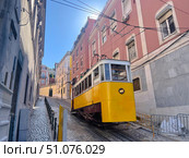 Iconic yellow funicular tram climbing a steep cobblestone street surrounded by colorful buildings. Стоковое фото, фотограф Виктор Ветошкин / Фотобанк Лори