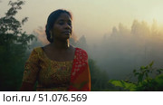 A woman dressed in traditional clothing enjoys the serene beauty of nature at dawn. Стоковое AI-видео, аниматор Данила Большаков / Фотобанк Лори