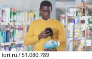 Before making purchase, African man buyer scan QR code on packaging of liquid detergent. Стоковое видео, видеограф Яков Филимонов / Фотобанк Лори