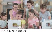 Teen girl sewing at machine in classroom with teacher support. Стоковое видео, видеограф Яков Филимонов / Фотобанк Лори